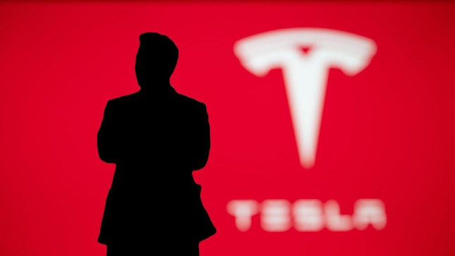 Elon Musk Tesla logosunun önünde gölgede